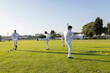 © Wavebreak Media - Male athletes performing synchronized high-leg kicks on grass training field with cones, copy space
