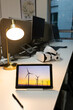 © Wavebreak Media - Tablet in protective case displaying wind turbines at sunset on desk with lamp and VR headset