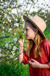 © Halfpoint - Young girl surrounded by trees smelling blooming flower on branch.