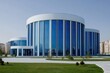 © Lunara Collective - Modern, circular building with large glass facade.  Exterior shot.  Vast expanse of light blue glass.  Concrete plaza in front.  Green lawn surrounds.  Modern architecture