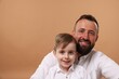 © New Africa - Family portrait of happy father and his son on beige background. Space for text