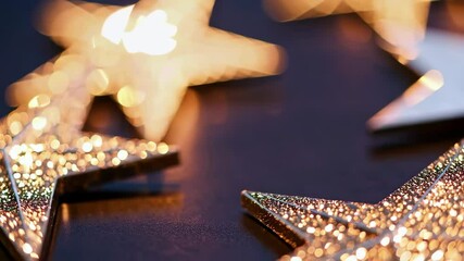 Wall Mural - Shimmering gold stars in motion on dark surface with soft bokeh effect