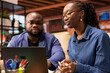 © DC Studio - African american couple sitting on couch to share a business idea, using modern technology and tools to analyze trends and boost success. Freelancers improving workflow efficiently.