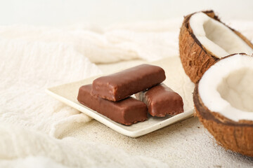 Wall Mural - Plate with tasty chocolate covered coconut candies on light background