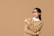 © Pixel-Shot - Portrait of young Asian businesswoman in eyeglasses pointing at something on beige background