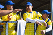 © Wavebreak Media - Three male baseball players leaning on chain-link fence in dugout, holding bat and towel