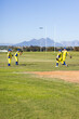 © Wavebreak Media - Male baseball teammates practicing catching fly ball on grass outfield near white rugby goalposts