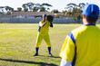 © Wavebreak Media - Diverse male teammates practicing catching baseball on field in yellow-blue uniforms with gloves