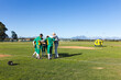 © Wavebreak Media - Male baseball players and coach huddling on pitcher's mound on baseball field with catcher's helmet