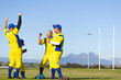 © Wavebreak Media - Diverse male teammates in yellow uniforms pumping fists on baseball field with glove, copy space