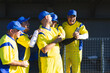 © Wavebreak Media - Diverse male teammates in jerseys laughing in dugout holding smartphone, glove and baseball