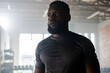 © Wavebreak Media - African American man wearing fitted black shirt pausing workout in studio with dumbbell rack