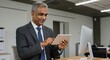 © Alamin Islam Adi  - Smiling mature businessman using tablet and desktop computer in modern office.