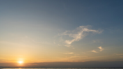 Wall Mural - sunset sky cloud over sea water background in evening with orange, yellow, blue sun light, horizon s