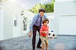 © Marko Geber - Happy father and son playing soccer or footbal outside of their home on their driveway and having fun