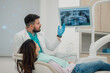 © Zamrznuti tonovi - Dentist showing teeth x ray to patient in modern clinic