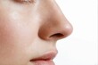 © piyawat - Closeup portrait of a woman's nose and lips with eyes closed on a white background, showcasing smooth wellgroomed skin.
