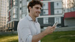 © Yuliia - Young Caucasian man holding mobile phone smartphone male walking going street guy thinking businessman solving addict business city student using gadget social media outdoor online internet chat app