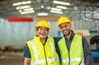 © BESTIMAGE - Two happy factory workers wearing hard hats and safety vests standing with arms crossed.