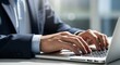 © Kamran-Studio - Hands typing on laptop computer keyboard. Businessman in suit working at desk in office. Using technologies in business.