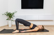 © Olha Tsiplyar - Woman practicing glute bridge yoga pose at home