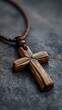© Daphne - Wooden cross necklace on stone surface with braided leather cord