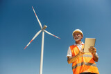 Low angle view of senior environmentalist with tablet standing near wind turbine. Low angle view of senior environmentalist with tablet standing near wind turbine.