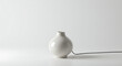 © Strother - Small, elegant white ceramic object with a minimalist design, featuring a cord, resembling a modern essential oil diffuser on a clean white surface.