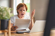 © Louis-Paul Photo - Sad frustrated senior woman pensioner having depressed look, holding hand on her face, calculating family budget, sitting at kitchen counter with laptop, papers, coffee, calculator and cell phone