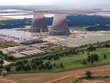 © AmazingAerialAgency - Aerial view of the industrial complex featuring cooling towers and solar panels blending with the landscape's green fields and brown patches creating a stark contrast, Trino, Piedmont, Italy.