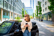 © sepy - A middle aged woman standing next to her car using a smartphone