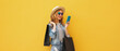 © rohappy - Beautiful happy young woman holding phone with black shopping bag, summer hat on yellow background
