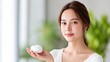 © Matcha_09 - Young Woman with Natural Beauty Holding Skincare Cream in Bright Indoor Setting Surrounded by Lush Greenery and Soft Light