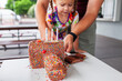 © Austockphoto - Three year old girl cutting birthday cake shaped like a camera with hundreds and thousands