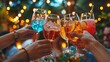 © GoshaMovies - A diverse group of friends enthusiastically toasts with colorful cocktails at a lively outdoor party at night, their hands meeting in celebration under the warm, festive glow of string lights