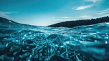 Abstract blue water scene featuring a close-up of sea waves and a shadowy forest horizon