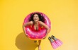 © Joedifries - Attractive mixed-race woman in vibrant red swimwear lounges seductively with floaties on isolated yellow background