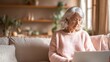 © Stokfish - The elderly woman enjoying her time on a laptop in a cozy living room.