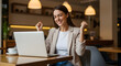 © Passionwith - Euphoric businesswoman celebrates online success in a cafe