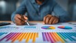 © SIRIN - Man analyzing colorful financial charts and graphs with a pen and calculator on a desk