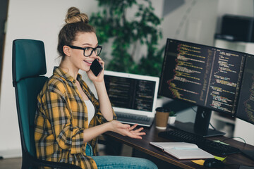 qualified female programmer working remotely, multitasking on a phone call, coding on computer scree