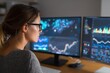 © Pavel - Woman analyzing business data on dual computer screens in a modern workspace during evening hours