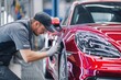 © Pavel - Auto body repair specialist working intently on a red luxury car at a modern repair facility during daylight hours