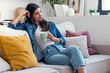 © nenetus - Pretty woman drinking a cup of coffee while sitting on couch in living room at home.