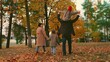 © Victoriia - Happy children play, walk holding hands with mom, dad, autumn park with yellow leaves. Kid on dads shoulders, mom son play together, holding hands in autumn outdoor. Family walk weekend dad child mom