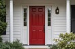 © Pete - Suburban home with red front door, white porch. White house two windows on right. Lawn with bushes, trees surrounds house, providing natural backdrop. Elevated perspective captures clear view of
