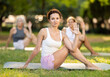 © JackF - Diligent young woman practicing lord of the fishes pose of yoga on mat in modern light green park at daytime