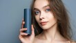 © Gabriel - A young woman with radiant skin and captivating blue eyes holds a sleek, cylindrical object against a serene gray backdrop. The portrait showcases the beauty of simplicity and grace.