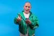 © Gatot - Senior Asian Man With Green Jacket Holding Smartphone While Giving Thumbs Up