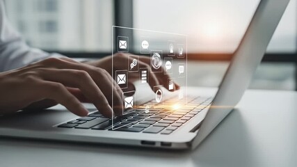 Hands typing on a laptop with a holographic interface displaying icons